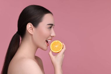 Pembe arka planda bir parça turuncu olan güzel bir genç kadın. Metin için boşluk