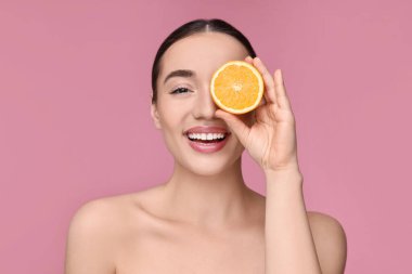 Pembe arka planda turuncu bir parça ile güzel bir genç kadın.