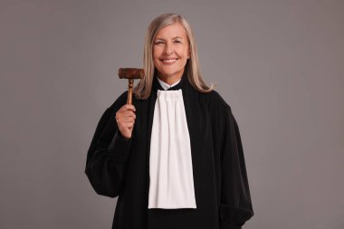 Gülümseyen kıdemli yargıç gri arka planda tokmağıyla