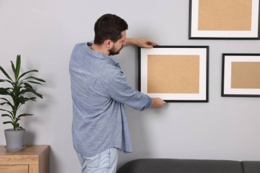 Evdeki gri duvara resim çerçevesi asan adam