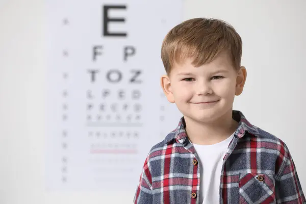 Cute little boy against vision test chart