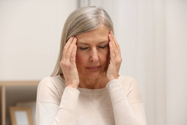 Menopause. Woman suffering from headache at home