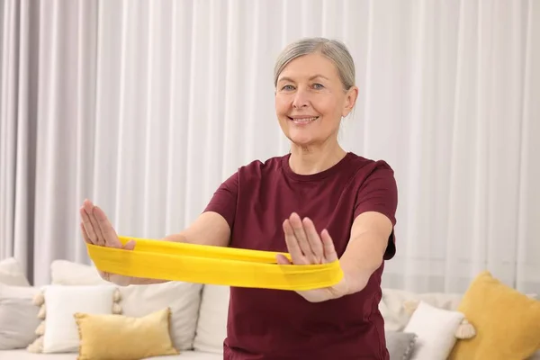 Senior woman doing exercise with fitness elastic band at home