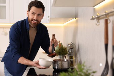 Adam mutfakta leziz domates çorbasını kaseye dolduruyor.