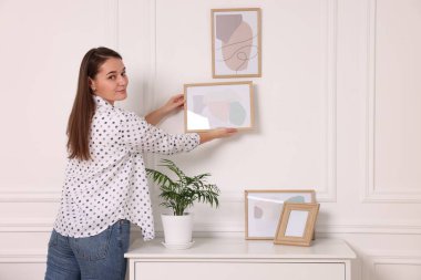 Evdeki beyaz duvara resim çerçevesi asan kadın