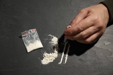 Ağır uyuşturucuya bağımlı bir adam ve bir dolar banknot yuvarlayarak gri dokuma masasında tüketime hazırlanıyor.