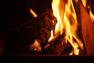 Koyu arka planda yakacak odunları olan şenlik ateşi, yakın plan.