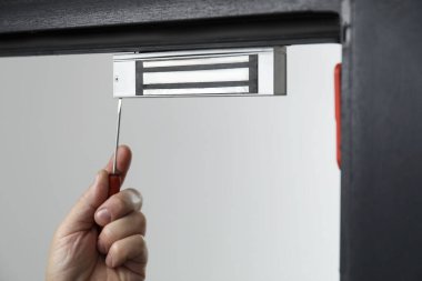 Tornavidalı bir adam elektromanyetik kapı kilidi yerleştiriyor, yakın plan. Ev güvenliği