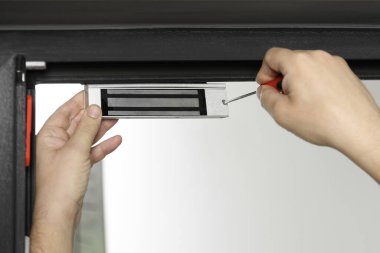 Tornavidalı bir adam elektromanyetik kapı kilidi yerleştiriyor, yakın plan. Ev güvenliği