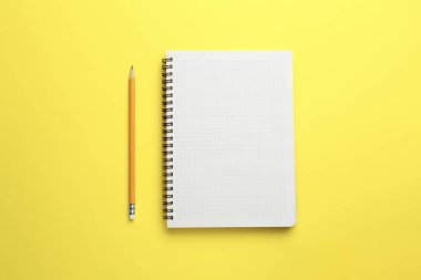 Sarı arkaplandaki defter ve kalem, üst görünüm