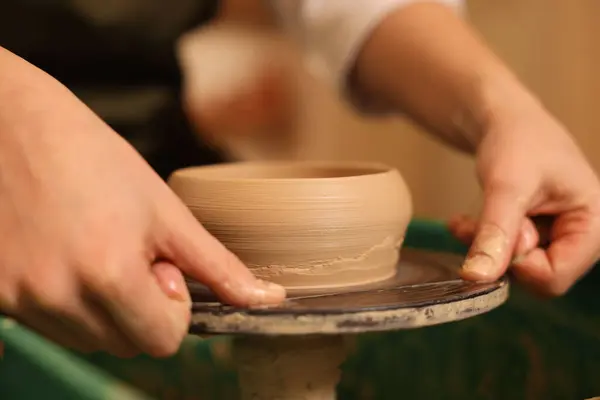 Clay crafting. Woman removing bowl from potter\'s wheel with thread