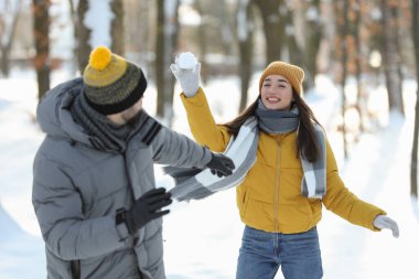 Mutlu çift kış günü dışarıda kartopu oynuyor.