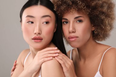 Gri arka planda sağlıklı cilde sahip güzel genç kadınlar.