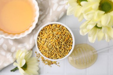 Düz kompozisyonda taze arı polenleri ve beyaz masanın üzerinde bal vardı.