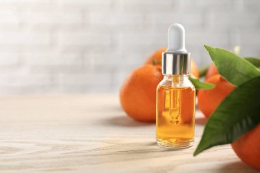Bir şişe mandalina yağı ve beyaz ahşap masada taze meyveler, yakın plan. Metin için boşluk