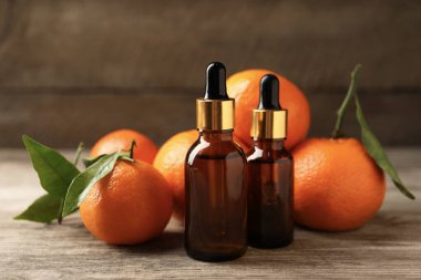 Mandalina yağı şişeleri ve ahşap masada taze meyveler.