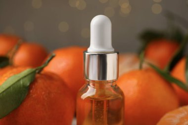 Bir şişe mandalina yağı ve arka planda taze meyveler, yakın plan.