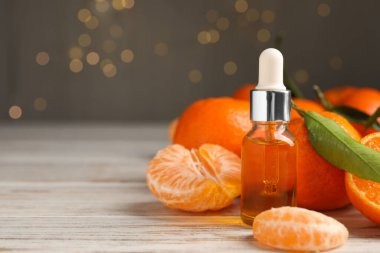 Bir şişe mandalina yağı ve beyaz ahşap masada taze meyveler, yakın plan. Metin için boşluk