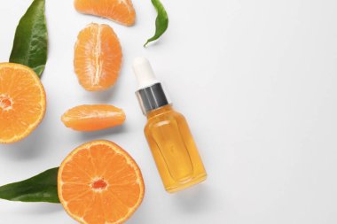 Aromatik mandalina yağı şişede, yapraklar ve narenciye meyveleri beyaz masada, düz yerde. Metin için boşluk