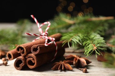 Ahşap masada farklı baharatlar ve köknar dalları, yakın plan.