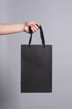 Gri arkaplanda kağıt poşet tutan kadın, yakın plan.