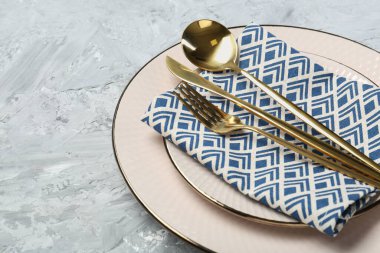 Temiz tabaklar, çatal bıçak takımı ve açık gri desenli masa, yakın plan. Metin için boşluk