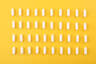 Turuncu arka planda birçok vitamin kapsülü var.