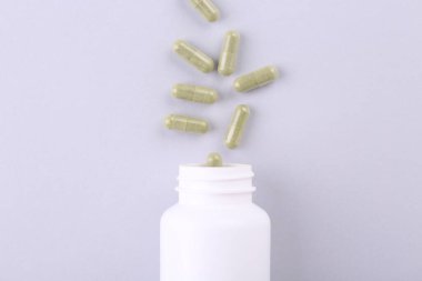 Beyaz zemin üzerinde vitamin kapsülleri olan kavanoz, üst görünüm