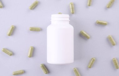 Beyaz zemin üzerinde vitamin kapsülleri olan kavanoz, düz yatar