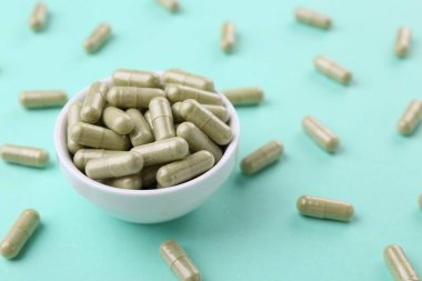 Turkuaz arka planda vitamin kapsüllü kase, yakın plan