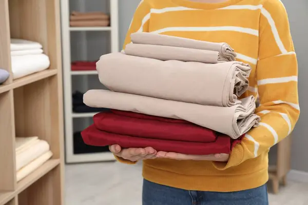 Woman with stack of bed linens in shop, closeup