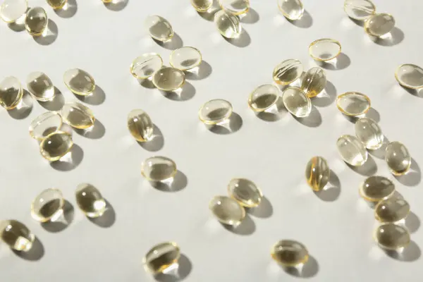 Many vitamin capsules on light background, closeup