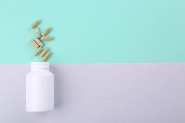 Renkli arka planda şişe ve vitamin kapsülleri, üst görünüm. Metin için boşluk