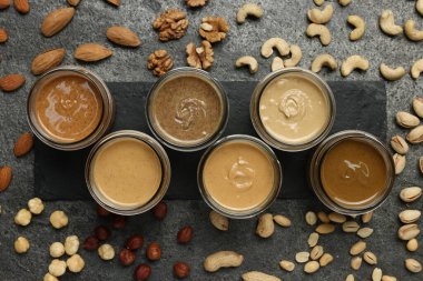 Kavanozlarda lezzetli fındık ezmesi ve gri masada çiğ fındık, düz yatıyordu.