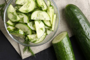 Cam kasede dereotlu salatalık ve masada taze sebzeler.