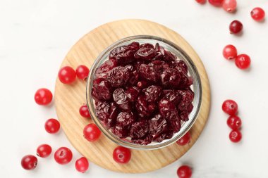 Lezzetli kuru kızılcıklar kasede ve taze olanlar beyaz masada, üst tarafta.