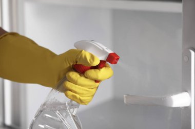 Sprey şişesi ve mikrofiber bez temizleme penceresi olan kadın, yakın plan.