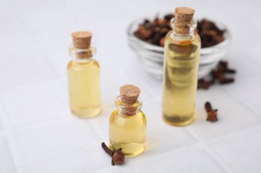 Şişelerdeki karanfil yağı ve beyaz döşemeli masada kurumuş tomurcuklar, yakın plan.