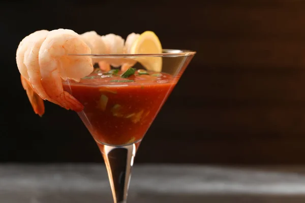 Tasty shrimp cocktail with sauce in glass on blurred background, closeup. Space for text