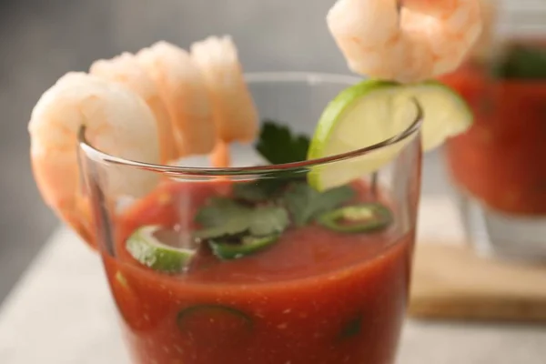 Tasty shrimp cocktail with sauce in glass and lime on table, closeup