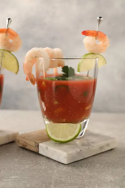 Tasty shrimp cocktail with sauce in glass and lime on light grey table