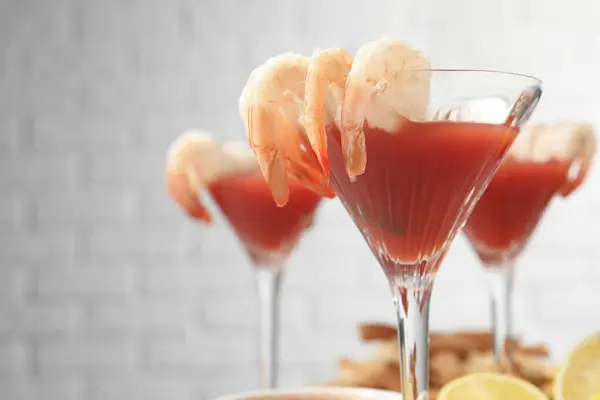 Tasty shrimp cocktail with sauce in glasses on table, closeup. Space for text