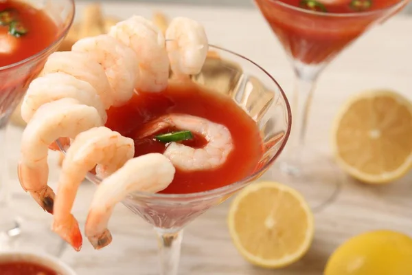 Tasty shrimp cocktail with sauce in glasses and lemon on table, closeup