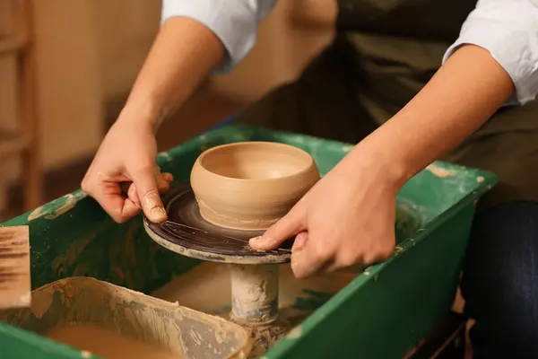 Clay crafting. Woman removing bowl from potter\'s wheel with thread