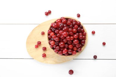 Taze kızılcıklar beyaz ahşap masada kasede, üst tarafta.