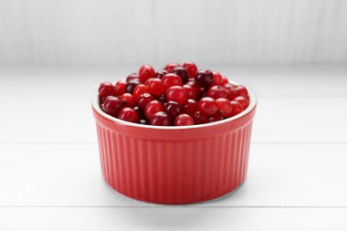 Taze kızılcıklar kasede beyaz ahşap masada, yakın plan.