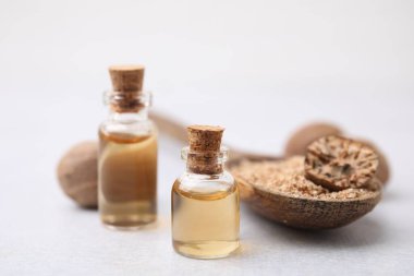 Nutmeg, temel yağ ve kaşık. Işık masasında yer fıstığı var. Yakın plan.