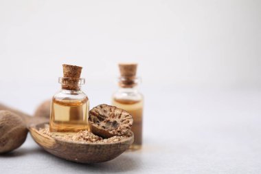 Nutmeg 'in temel yağı ve kaşığı. Işık masasında yer fıstığı var. Yakın plan. Metin için boşluk