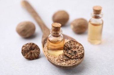 Nutmeg, temel yağ ve kaşık. Işık masasında yer fıstığı var. Yakın plan.