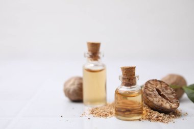 Nutmeg esaslı yağ ve fındıklar beyaz masada. Metin için boşluk